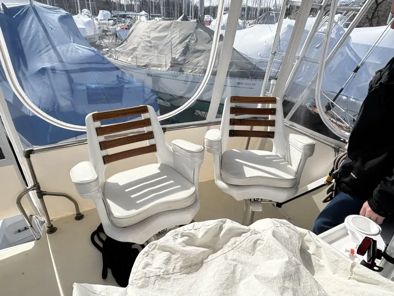 Slide: The Image of Two white chairs on a 1973 Viking boat deck, surrounded by covered boats. - 10