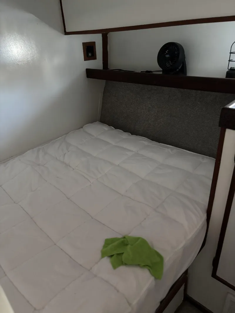 Slide: The Image of Cozy cabin bed in a 1973 Viking boat with white bedding and a green cloth. - 37