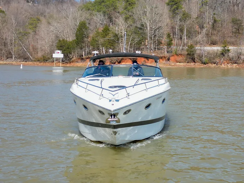 Slide: The Image of 2004 Cobalt 360 boat cruising on a calm lake with forested shoreline. - 3