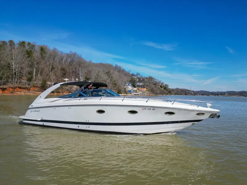 Slide: The Image of 2004 Cobalt 360 boat cruising on a lake with scenic forested shoreline. - 7