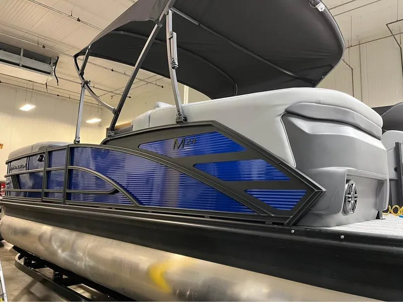 Slide: The Image of 2025 Bennington M 24 Fastback SE pontoon boat with blue accents in a showroom. - 1