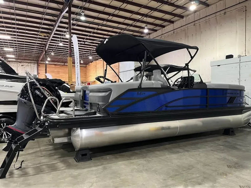 Slide: The Image of 2025 Bennington M 24 Fastback SE pontoon boat in a showroom, featuring sleek design and canopy. - 4