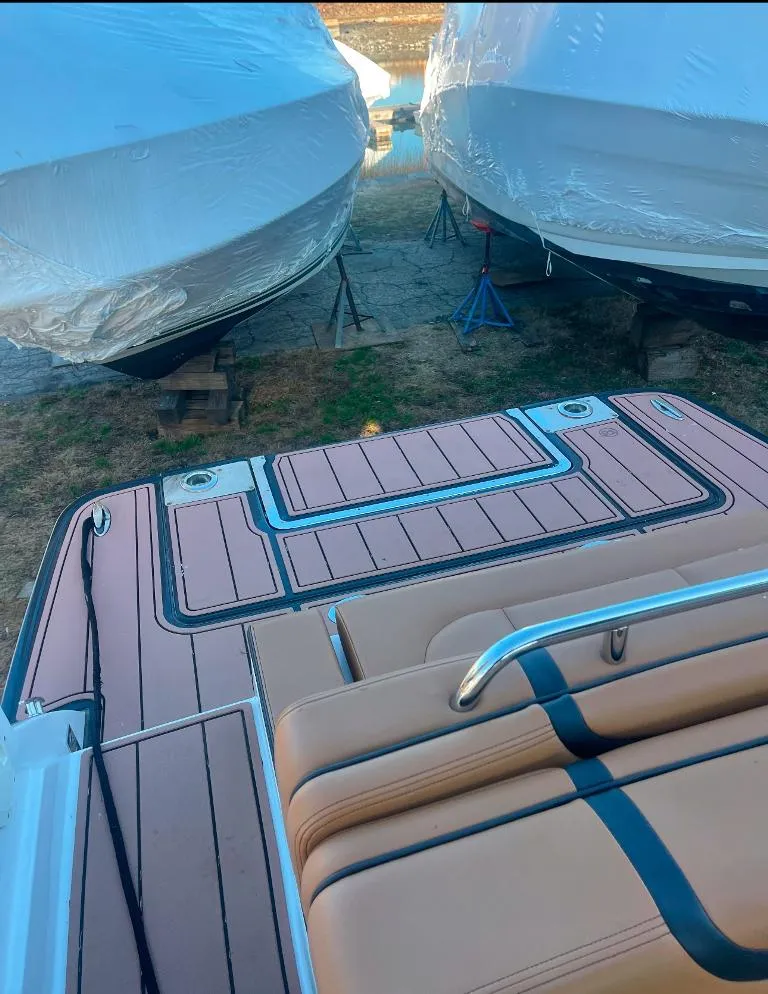Slide: The Image of 2021 Chaparral 267 SSX boat with tan seating and deck, docked between two covered boats. - 7