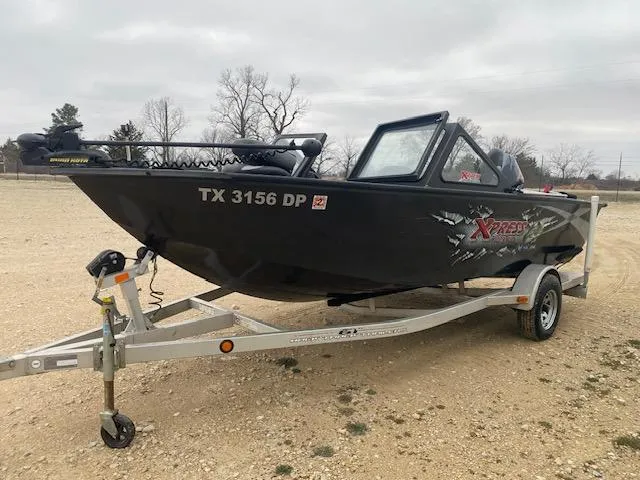 Slide: The Image of 2009 Xpress DVX175 boat on trailer, black exterior, parked on gravel. - 2