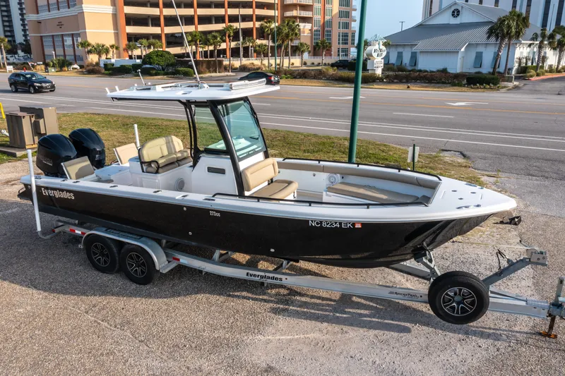 The Image of 2019 Everglades 273CC boat on trailer, parked near a road with buildings in background. - 0