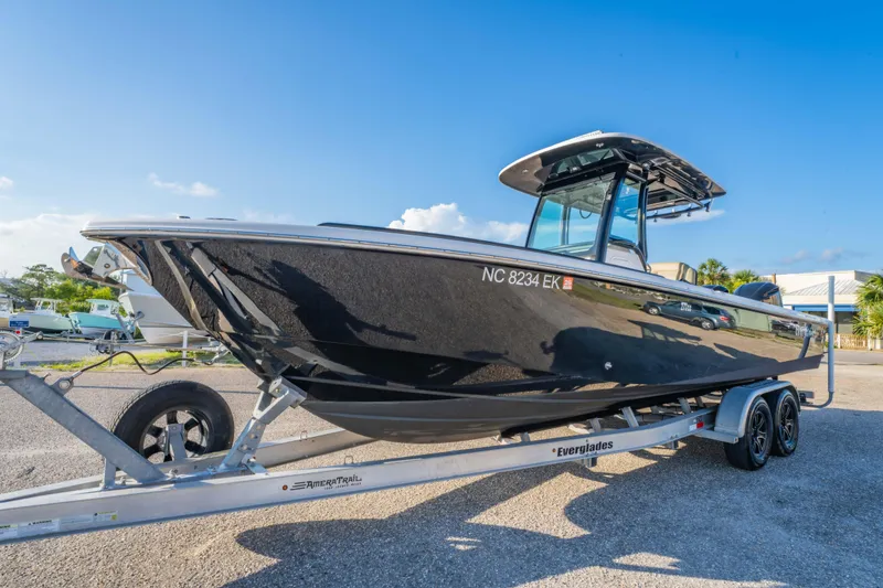 Slide: The Image of 2019 Everglades 273CC boat on trailer, sleek black design, sunny day. - 1