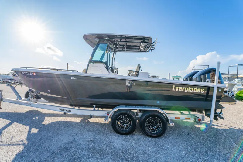 Slide: The Image of 2019 Everglades 273CC boat on trailer, front view, parked outdoors under clear blue sky. - 12