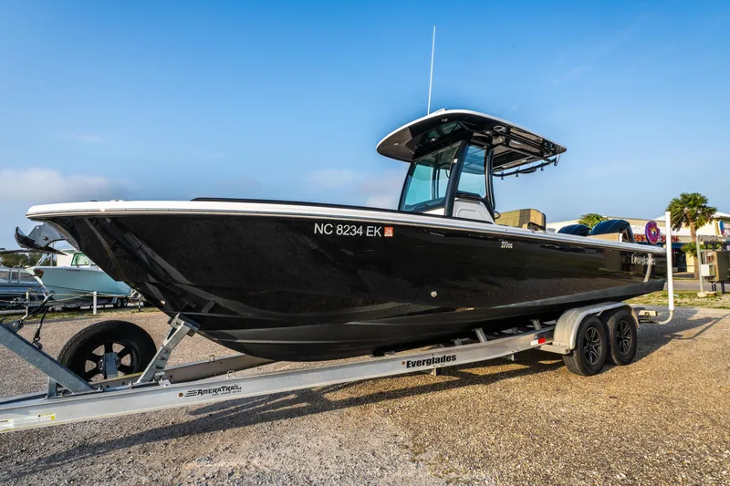 Slide: The Image of 2019 Everglades 273CC boat on trailer, black hull, parked outdoors. - 6