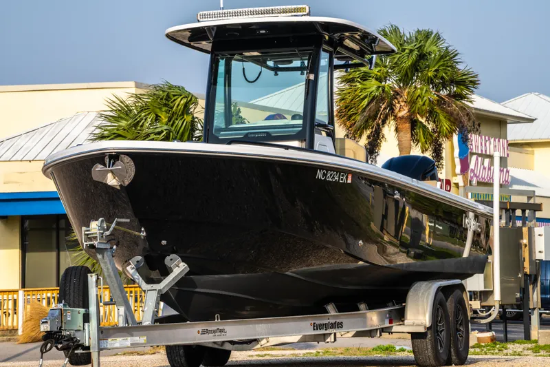 Slide: The Image of 2019 Everglades 273CC boat on trailer, parked near palm trees and buildings. - 8