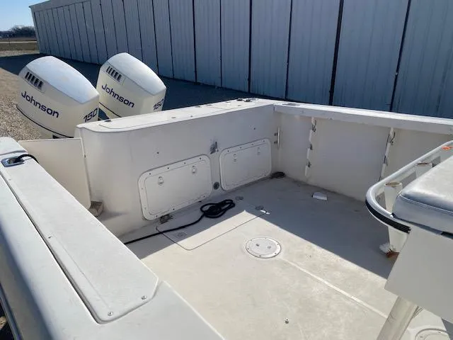 Slide: The Image of 1997 Pro-Line 240 Center Console boat with dual Johnson 150 engines, docked near storage units. - 9