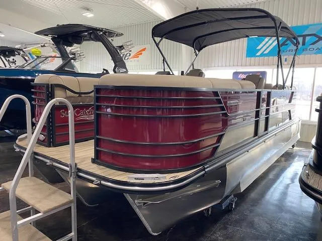 Slide: The Image of 2025 SunCatcher Elite 324 RC pontoon boat in showroom, featuring sleek design and canopy. - 2