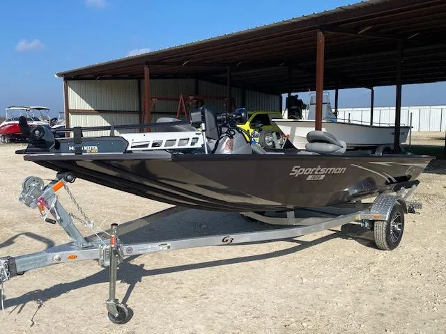 Slide: The Image of 2025 G3 Sportsman 1610 boat on trailer, parked outdoors under a metal shelter. - 2