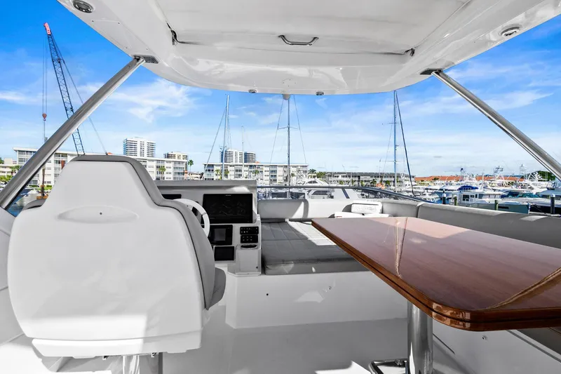 Slide: The Image of 2019 Azimut 50 Flybridge yacht interior with helm, seating, and table, overlooking marina. - 34