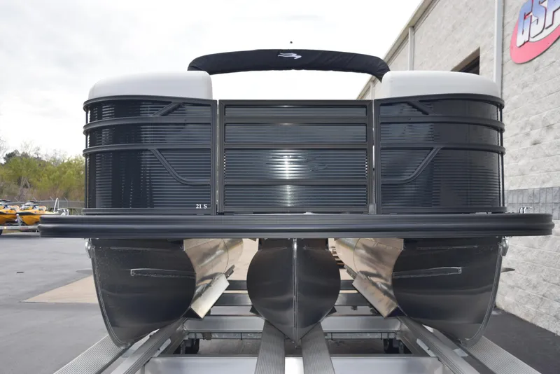 Slide: The Image of 2025 Bennington 21 SL pontoon boat on trailer, front view, parked near building. - 3