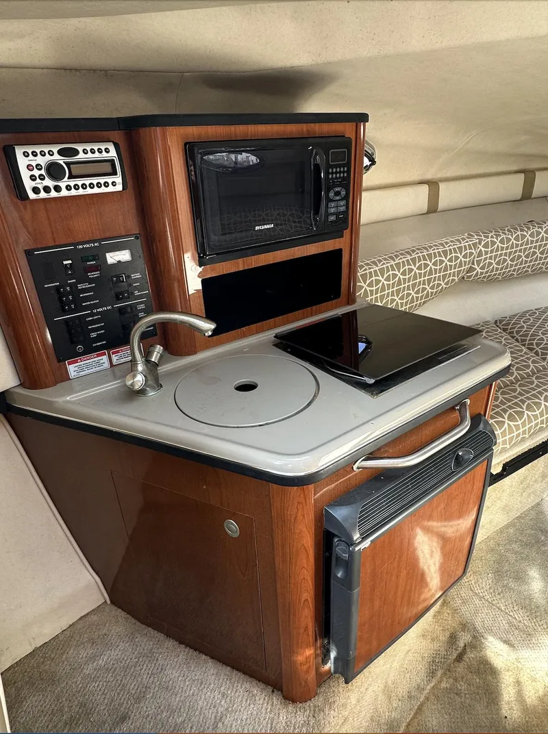 Slide: The Image of 2007 Sea Ray 240 Sundancer cabin with kitchenette, featuring sink, microwave, and compact fridge. - 33