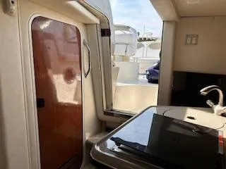 Slide: The Image of Interior view of 2007 Sea Ray 240 Sundancer boat, featuring a kitchenette and cabin door. - 43