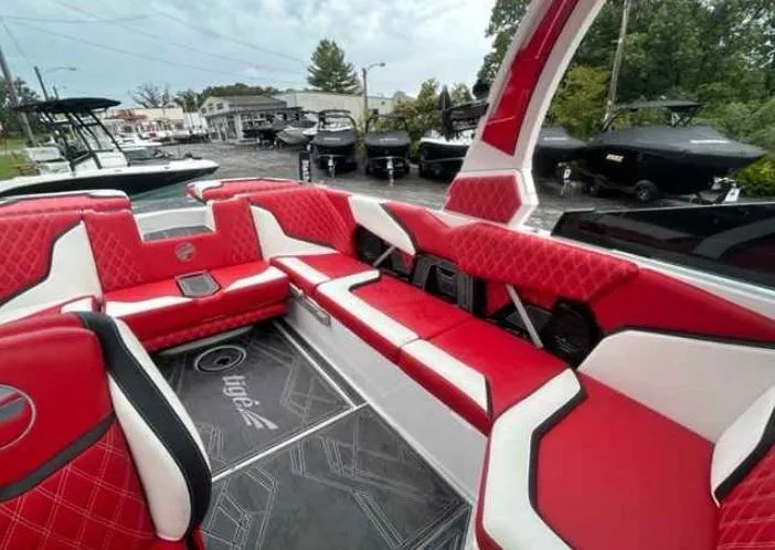 Slide: The Image of 2024 Tigé 24RZX boat interior with red and white seating, parked outdoors. - 3