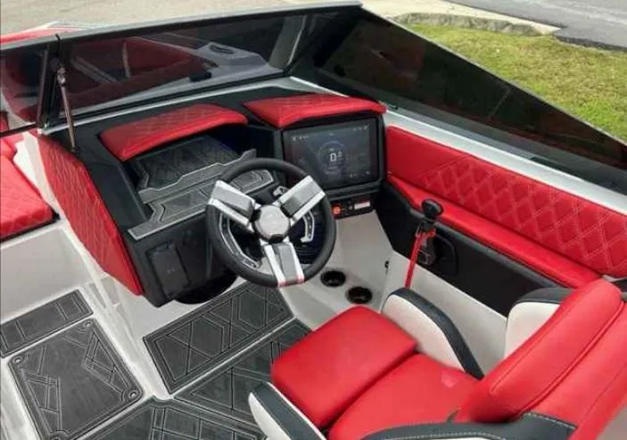 Slide: The Image of 2024 Tigé 24RZX boat interior with red and black upholstery, modern steering, and dashboard. - 6
