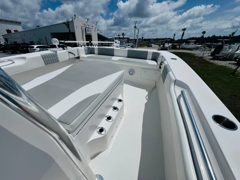 Slide: The Image of 2022 Twin Vee 310 CC GF Classic boat interior with cushioned seating under a cloudy sky. - 15