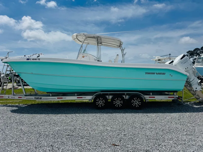 Slide: The Image of 2022 Twin Vee 310 CC GF Classic boat on trailer, turquoise hull, clear sky background. - 6