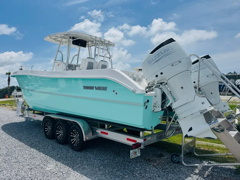 Slide: The Image of 2022 Twin Vee 310 CC GF Classic boat on trailer, featuring dual Suzuki outboard engines. - 8