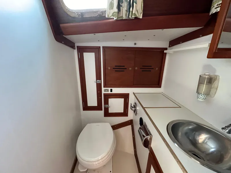 Slide: The Image of 1978 Hinckley Bermuda 40 MK III yacht bathroom with sink, toilet, and wooden cabinetry. - 17