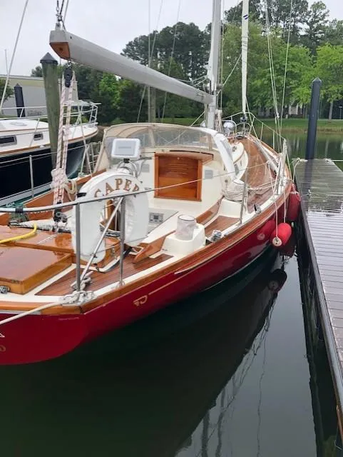 Slide: The Image of 1978 Hinckley Bermuda 40 MK III sailboat docked, featuring a red hull and wooden deck. - 27
