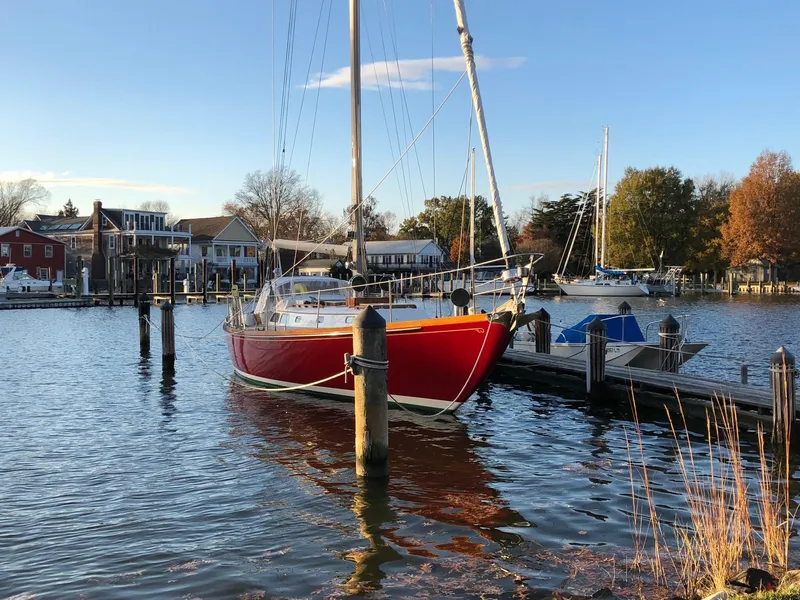 Slide: The Image of Red 1978 Hinckley Bermuda 40 MK III sailboat docked in a serene marina setting. - 7