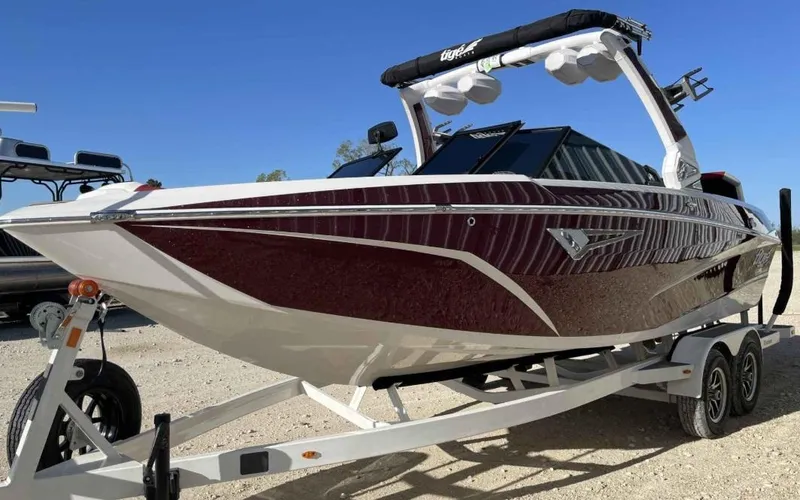 Slide: The Image of 2024 Tigé Z3 boat on trailer, sleek design, maroon and white color, ready for water sports. - 2