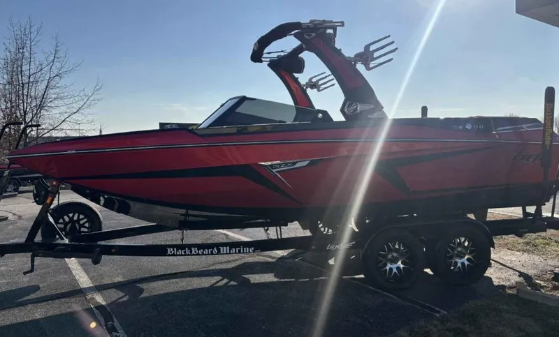 Slide: The Image of 2023 Tigé 22RZX boat in red on a trailer, parked outdoors. - 3