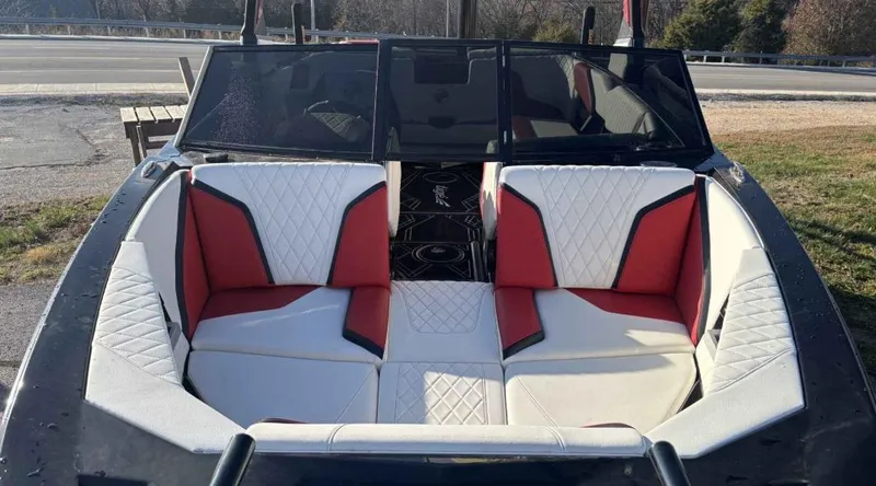 Slide: The Image of 2023 Tigé 22RZX boat interior with red and white seating, parked outdoors. - 4
