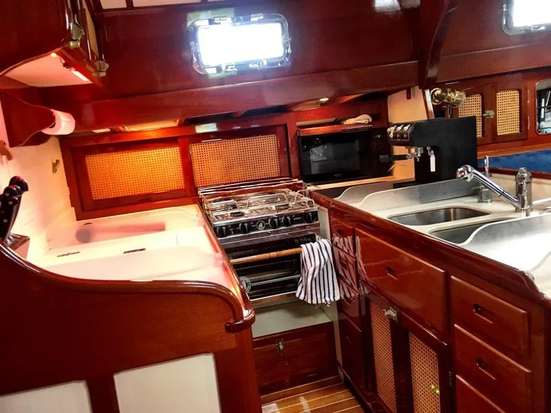Slide: The Image of Interior of 2000 Cherubini Schooner, featuring a well-equipped kitchen with wooden cabinetry. - 11