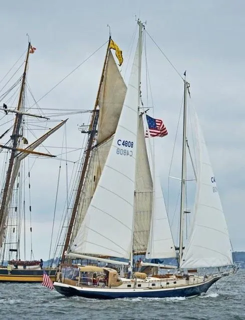 Slide: The Image of Cherubini Schooner 2000 sailing with American flag on a cloudy day. - 14