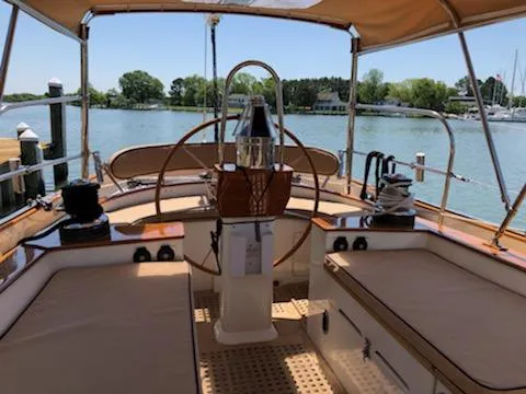 Slide: The Image of Cherubini Schooner 2000 cockpit with wooden helm, docked by serene waters. - 16