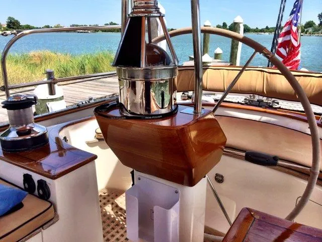 Slide: The Image of Cockpit of 2000 Cherubini Schooner with polished wood and nautical equipment, docked by the water. - 17