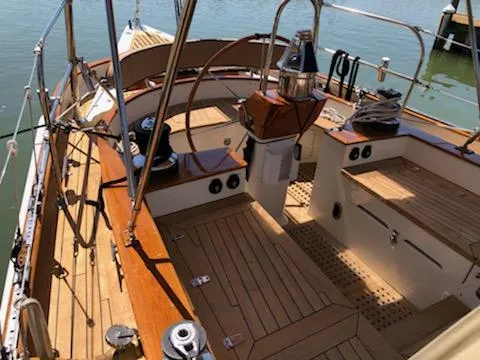 Slide: The Image of Cherubini Schooner 2000 sailboat cockpit with wooden deck and steering wheel, docked by the water. - 20