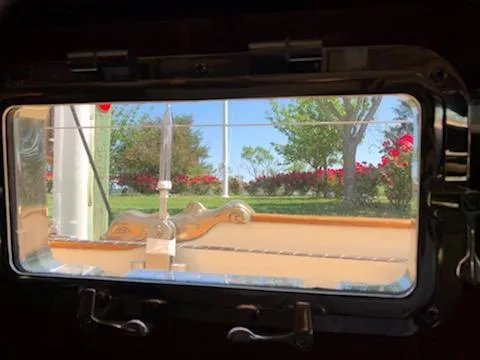 Slide: The Image of View through a Cherubini Schooner 2000 porthole, showcasing a garden with trees and flowers. - 24