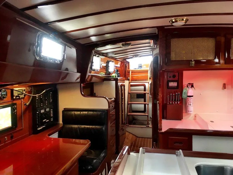Slide: The Image of Interior of 2000 Cherubini Schooner, featuring polished wood, navigation equipment, and cozy seating. - 25