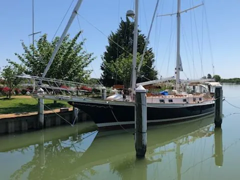 Slide: The Image of Cherubini Schooner 2000 docked on calm water, surrounded by trees and clear sky. - 44