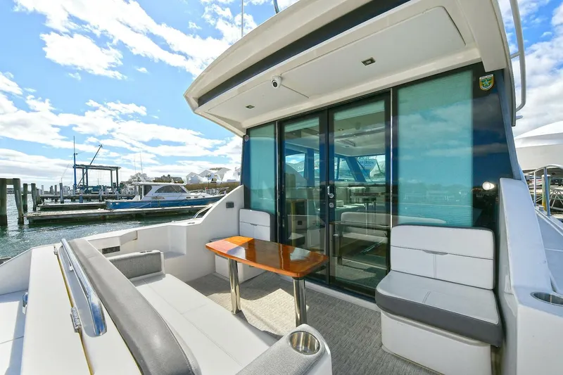 Slide: The Image of 2018 Tiara Yachts 39 Coupe with sleek seating and table on deck, docked at marina. - 11