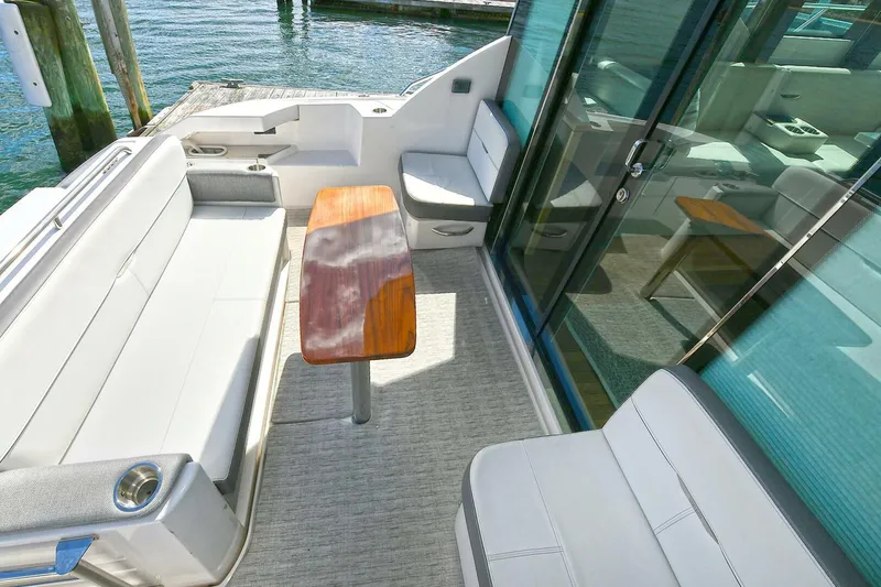 Slide: The Image of 2018 Tiara Yachts 39 Coupe deck with seating and wooden table, dockside view. - 12