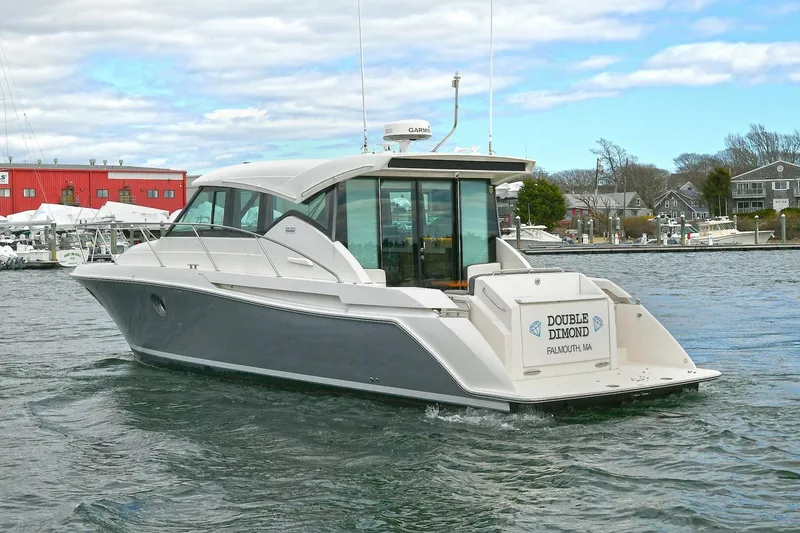 Slide: The Image of 2018 Tiara Yachts 39 Coupe cruising in a marina with red building backdrop. - 6
