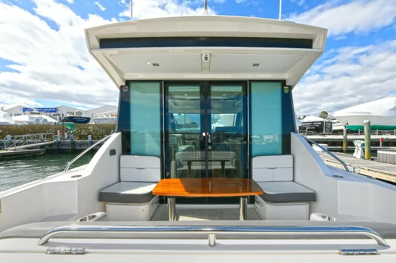 Slide: The Image of 2018 Tiara Yachts 39 Coupe with outdoor seating and table, docked under a blue sky. - 9