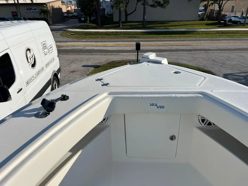 Slide: The Image of 2018 SeaVee 320B boat bow view with SeaVee logo, parked near branded van. - 14