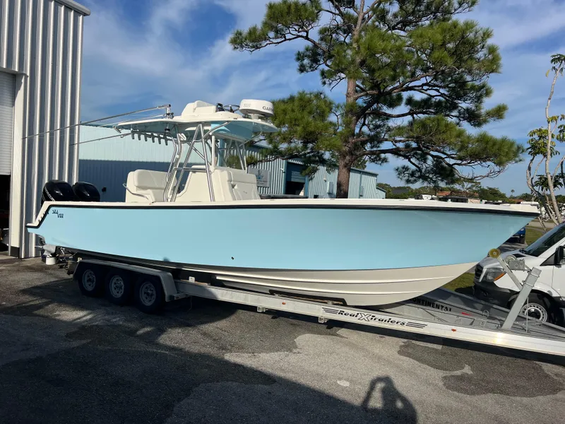 Slide: The Image of 2018 SeaVee 320B boat on trailer, light blue hull, parked outdoors. - 2