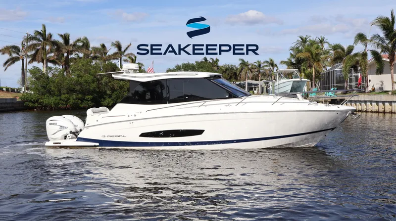 Slide: The Image of 2023 Regal 36 XO boat on water with Seakeeper logo, surrounded by palm trees. - 0