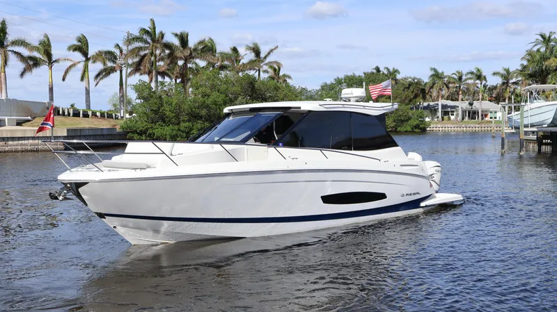 Slide: The Image of 2023 Regal 36 XO yacht cruising on a sunny day with palm trees in the background. - 2