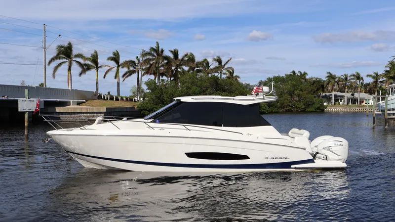 Slide: The Image of 2023 Regal 36 XO yacht cruising on a scenic waterway with palm trees. - 3