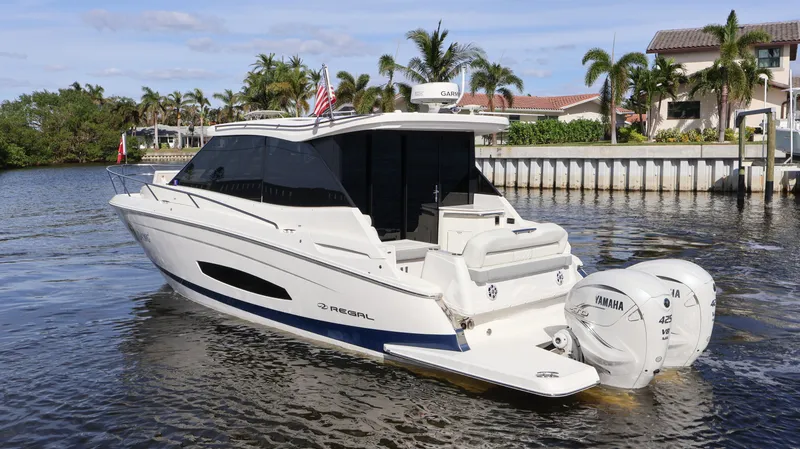Slide: The Image of 2023 Regal 36 XO boat on water, featuring twin Yamaha engines, near waterfront homes. - 4