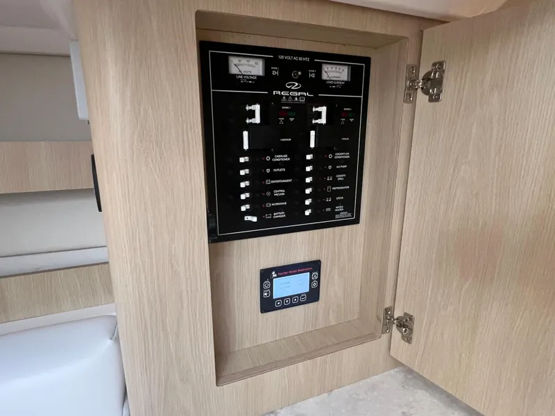 Slide: The Image of Electrical control panel inside 2023 Regal 36 XO boat, featuring modern wood cabinetry. - 49